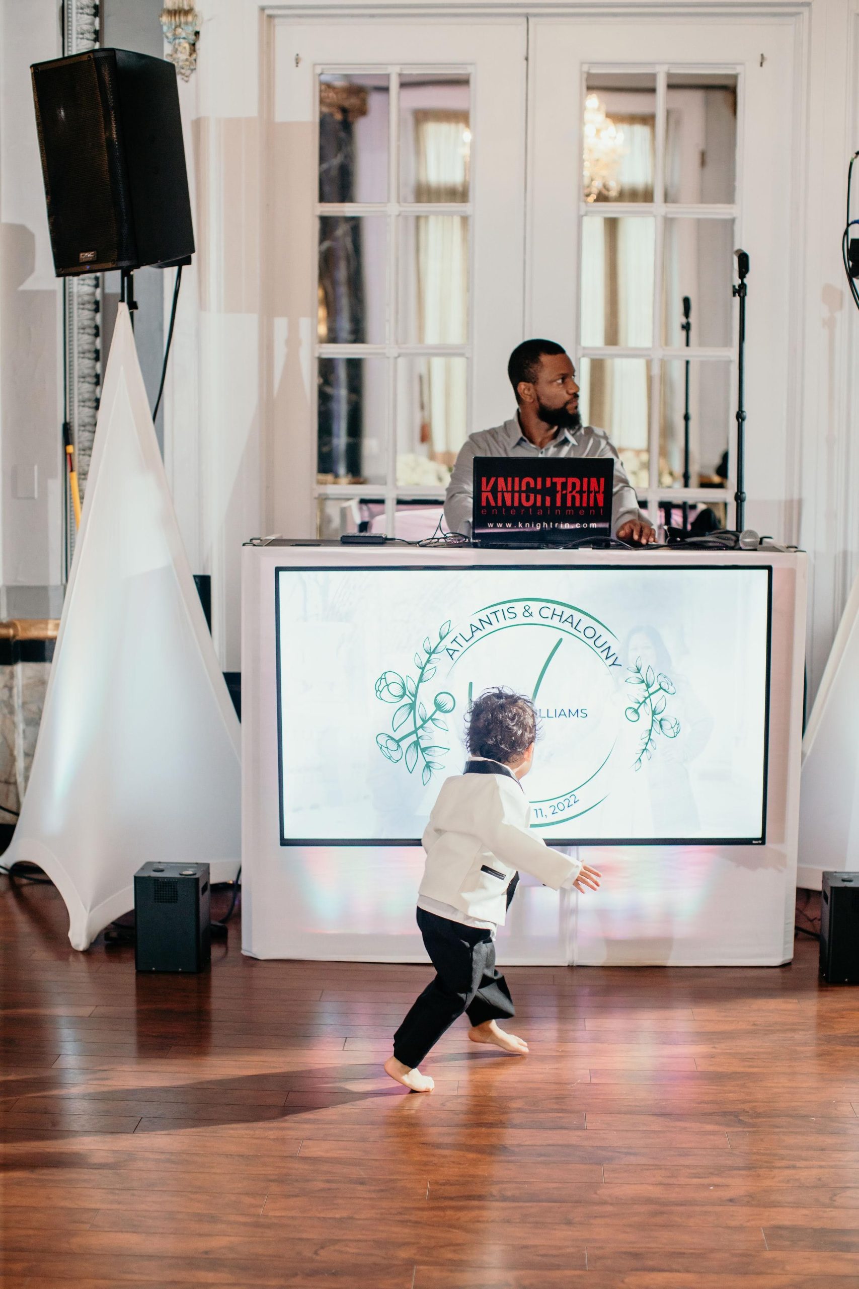 Knightrin wedding DJ in DC: booth with a monogram screen and uplighting at a ballroom reception as the ring bearer dances Knightrin wedding DJ in DC: booth with a monogram screen and uplighting at a ballroom reception as the ring bearer dances
