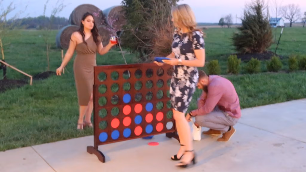 People play giant Connect Four outdoors at a lively private party.