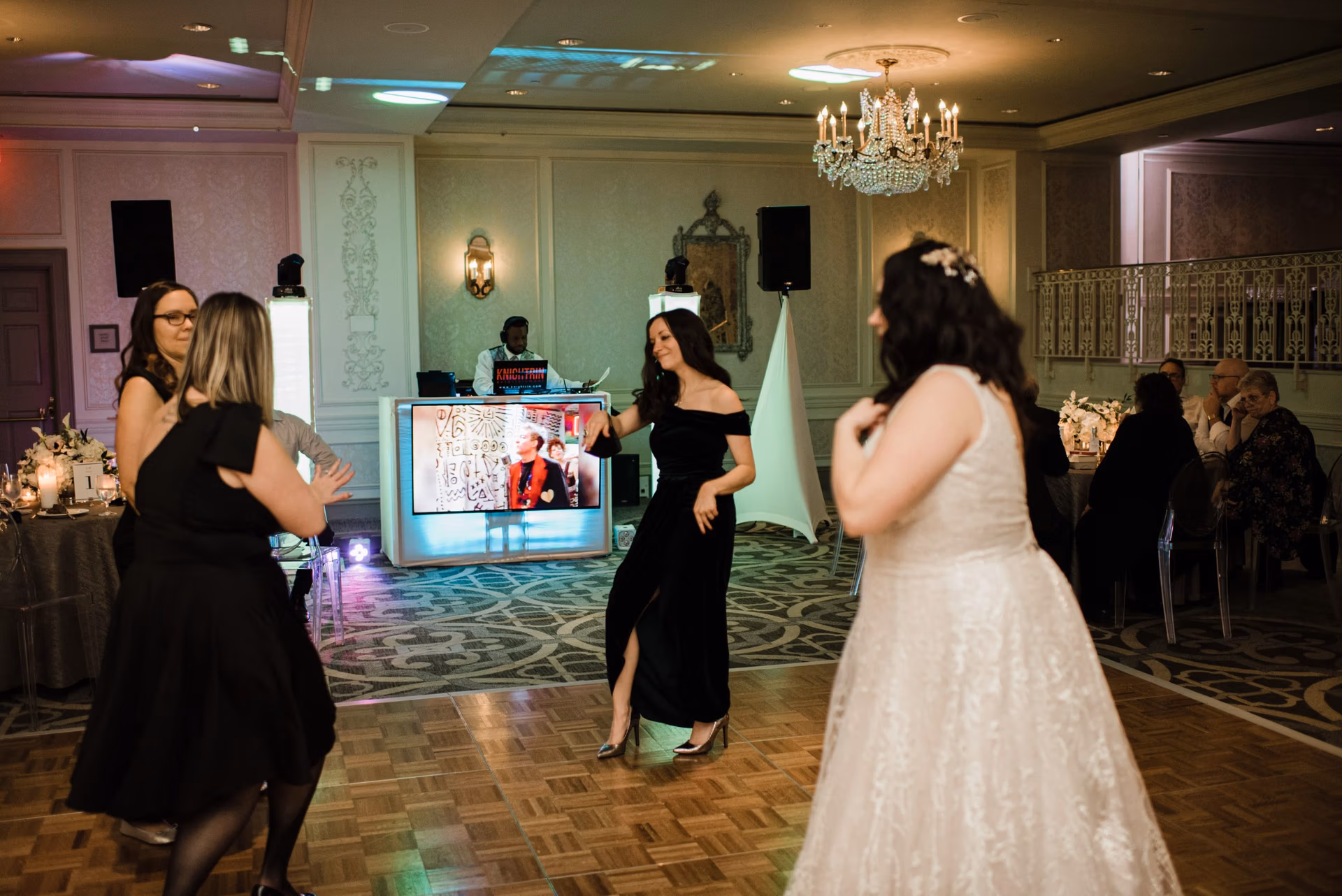 Bride dancing in her gown on a ballroom dance floor with the DJ booth glowing behind her Bride dancing in her gown on a ballroom dance floor with the DJ booth glowing behind her